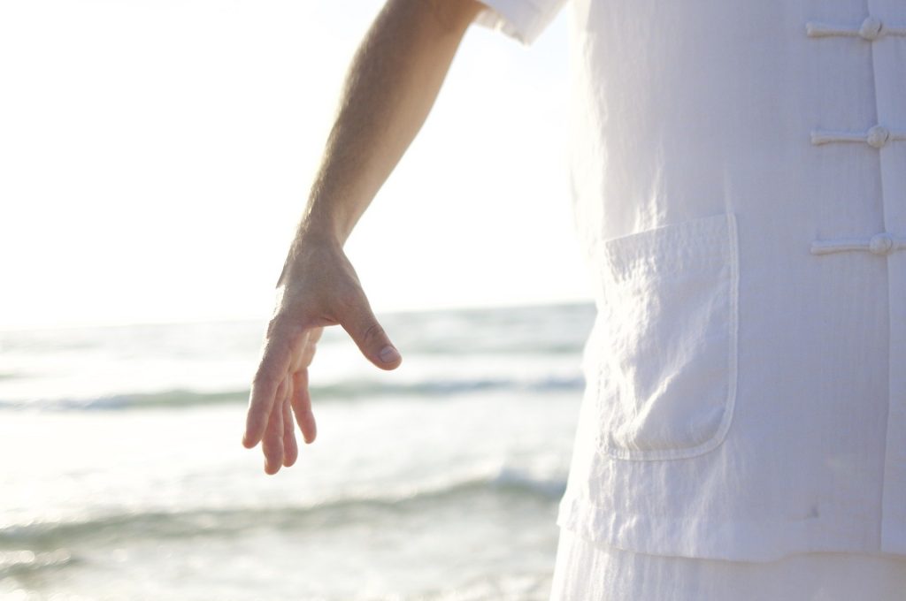 Main d'une personne faisant du Qi Gong sur la plage